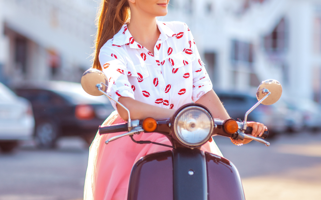 Foto de uma mulher andando no conhecido veículo da Itália chamado "Vespa"