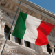 foto de uma bandeira italiana com um edifício antigo atrás simbolizando a unificação da itália.